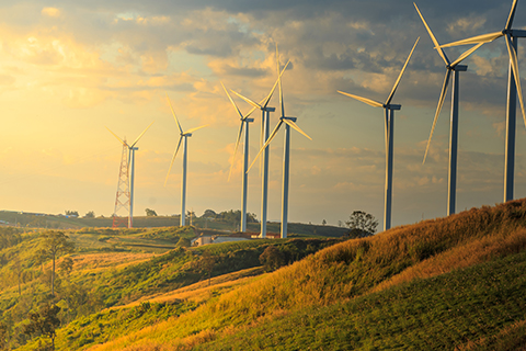 Sunset sinking over the hills of a wind turbine farm. 